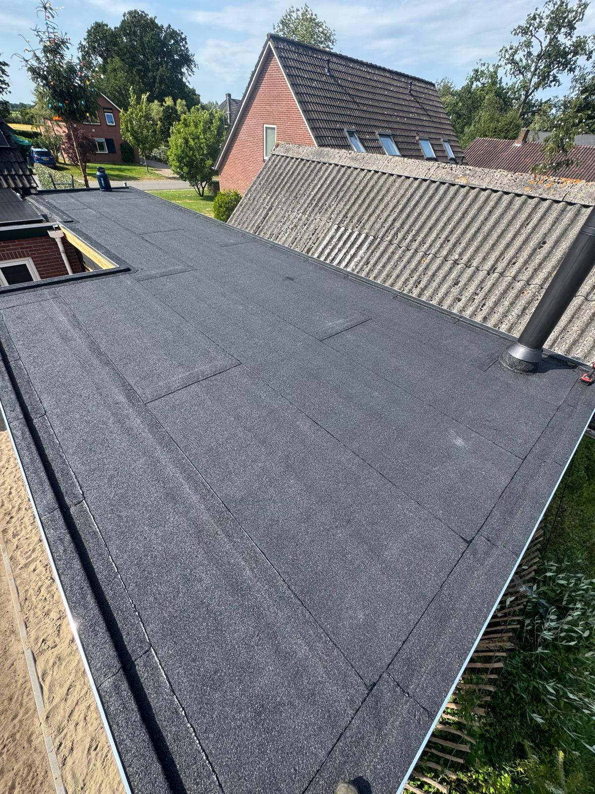 Afgewerkt plat dak met nieuwe zwarte bitumen dakbedekking